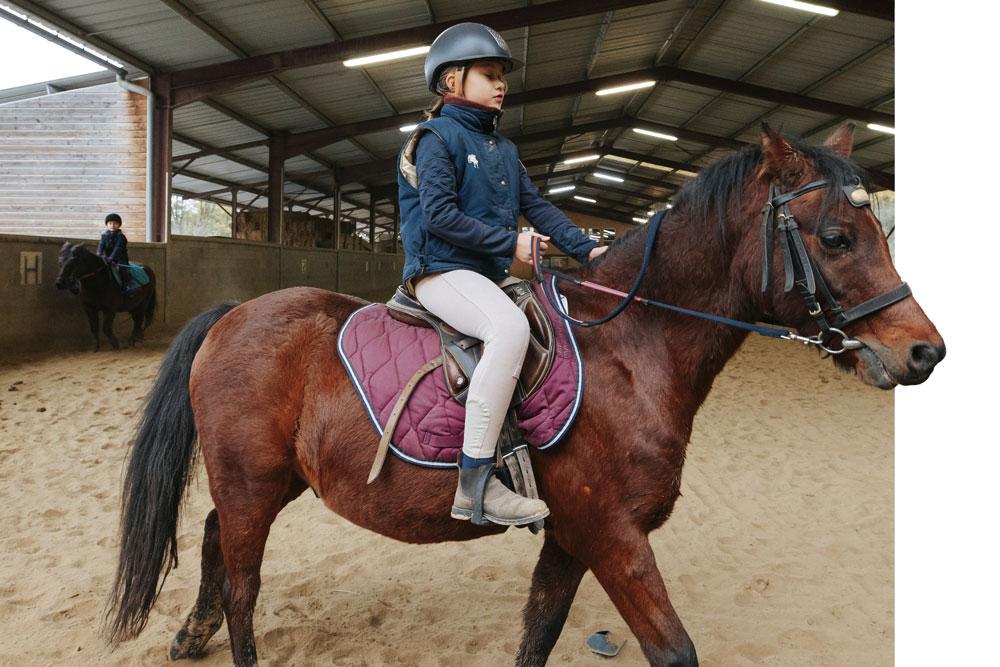 Une jeune fille monte sur un cheval dans le centre équestre du Couzon