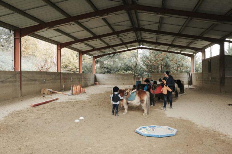 Des enfants s'apprêtent à monter dans le manège à poneys du centre équestre du Couzon