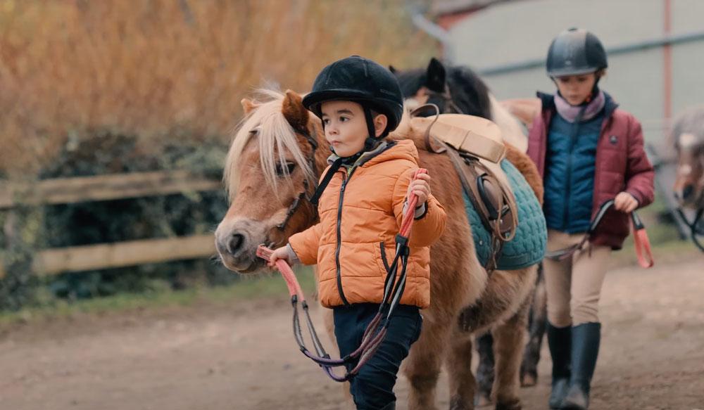 De jeunes enfants guident leur poney vers le manège du centre équestre du Couzon