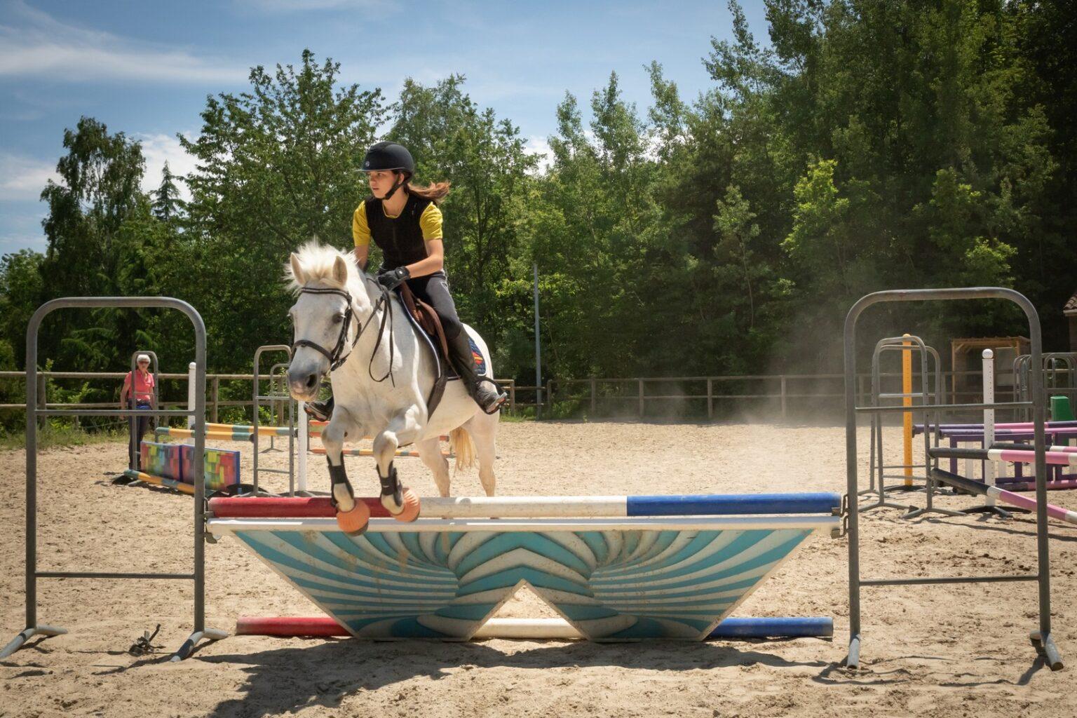 Une femme sur son cheval saute au-dessus d'un obstacle au centre équestre du Couzon