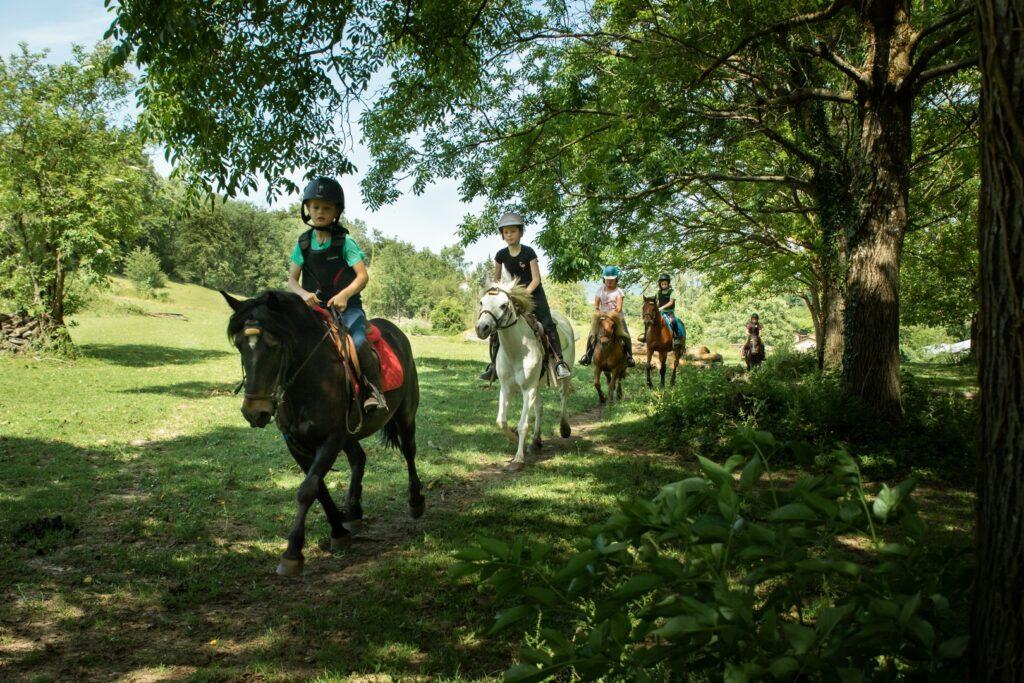 Des enfants sur leurs chevaux avancent en file indienne au centre équestre du Couzon