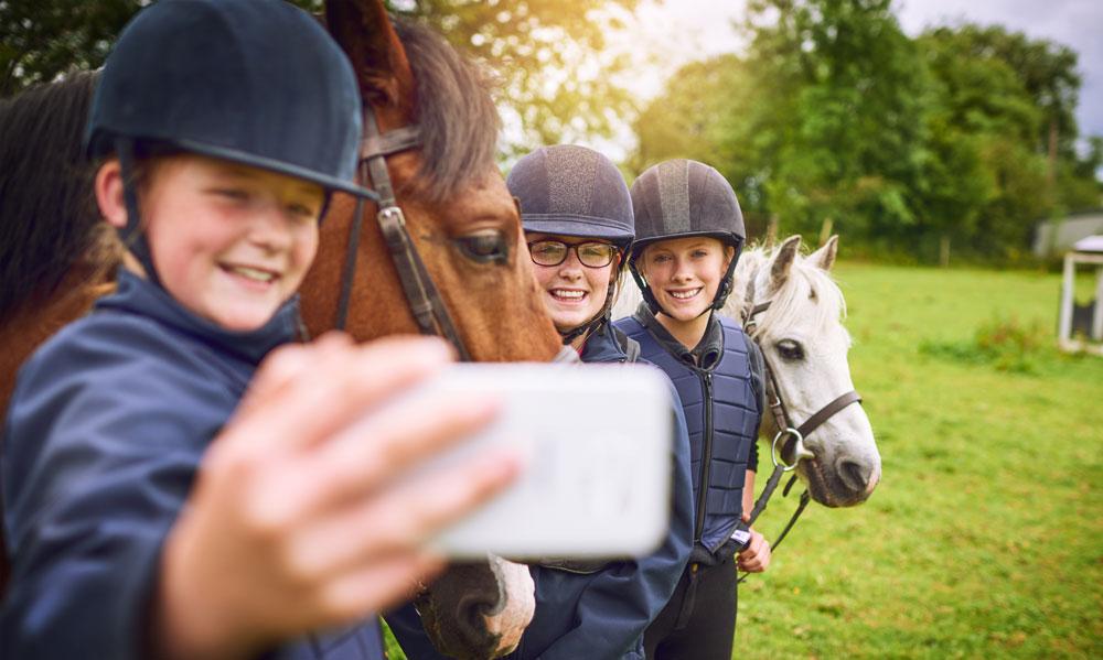 Des enfants font un selfie devant des chevaux au centre équestre du Couzon